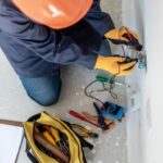Man testing electricity with multimeter using safety equipment