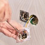 Hands of an electrician installing an electrical outlet in a new house. Assembly of the electrical network in the room, installation of the electrical network